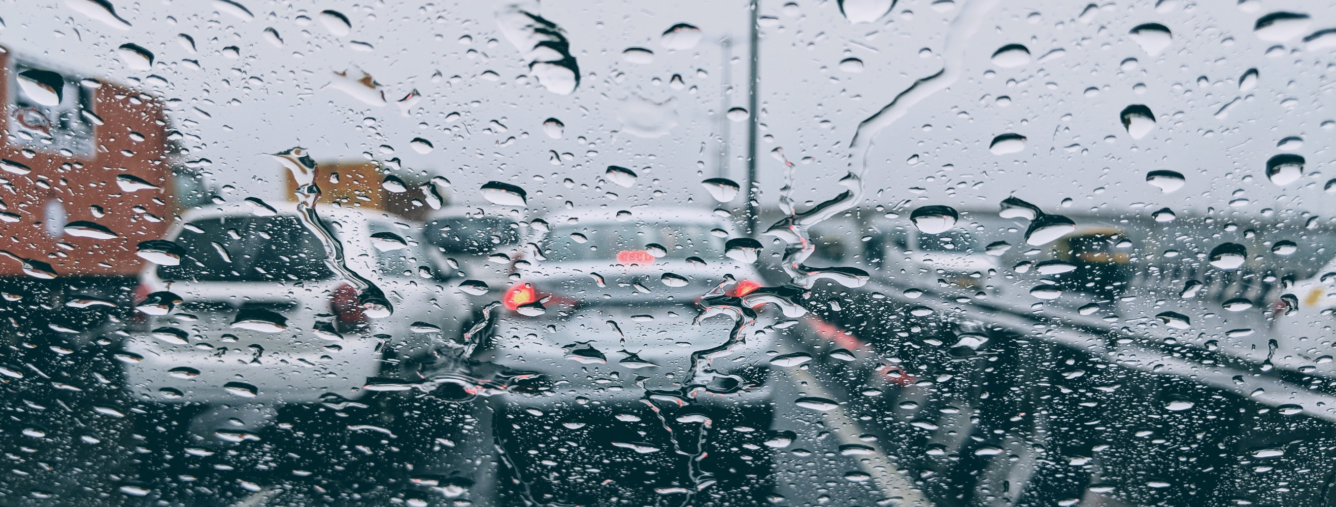 Krople deszczu na szybie bez włączonych wycieraczek samochodowych.